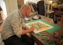 Load image into Gallery viewer, Mark Hearld signs his original screen print Marwari Horse. He sits at his studio desk, with scissors, cut paper and crayons littering the worktop.