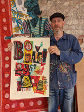 Load image into Gallery viewer, Jonny Hannah holds up his screenprint Boy annd Bicycle in his studio.
